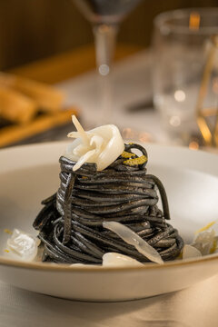 Gourmet presentation of Italian spaghetti with squid ink served on a restaurant table. 
