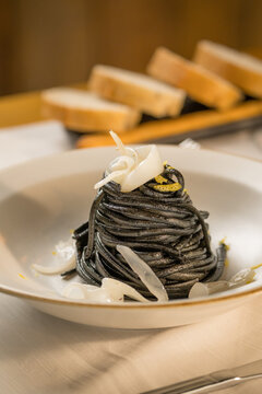 Gourmet presentation of Italian spaghetti with squid ink served on a restaurant table. 