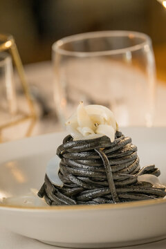 Gourmet presentation of Italian spaghetti with squid ink served on a restaurant table. 