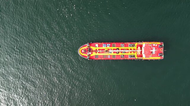 Water transport ship crossing frame in the top-down drone shot