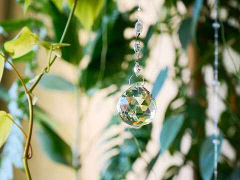 Close-up of a transparent faceted crystal suncatcher in the shape of a ball.