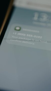 Message about a package being on hold and asking to confirm delivery on smartphone screen. Smishing scam. Ethical hacking concept