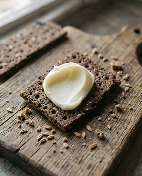 A close up of two pieces of bread with a creamy substance on top. Swedish crispbread slice butter close.