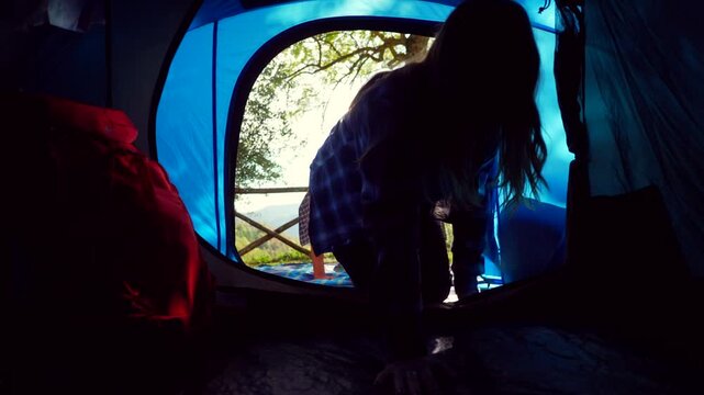 Young couple holding hands entering camping tent. Happy couple of campers entering their blue tent holding hands after a day of hiking in nature