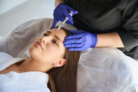 Beautiful woman getting facial injection in salon
