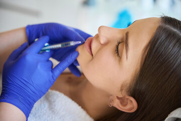 Fototapeta premium Injection procedure for lip augmentation, close up