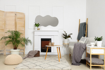 Obraz premium Interior of light living room with mirror, grey sofa and fireplace