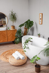 Obraz premium Interior of bathroom with green plants, sink and bathtub