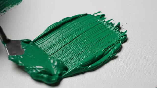 Textured green oil paint spread across canvas surface with palette knife creating artistic strokes