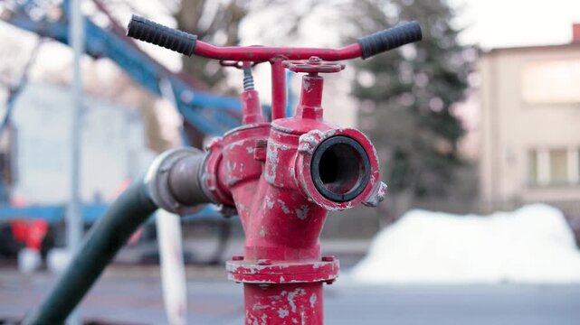 Close-up of a red fire hydrant standpipe with water dripping, located at an urban utility maintenance site. Concept of industrial repair and infrastructure work. High quality 4k footage