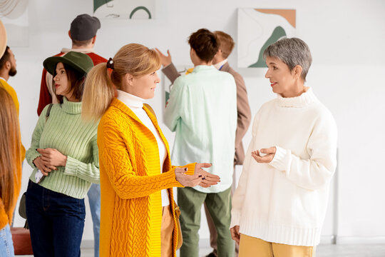 Mature women talking at exhibition in art gallery