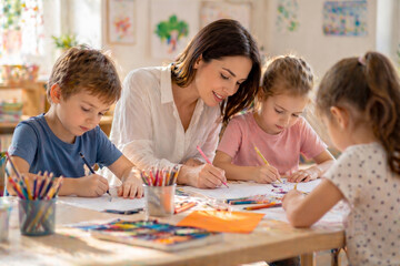 Fototapeta premium Teacher helping children with drawing and arts in classroom, creative education