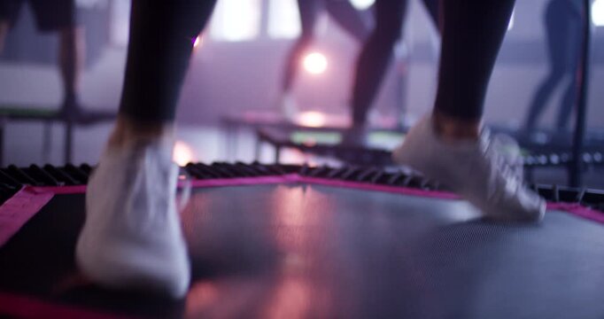 Feet of several people jumping in unison on mini trampolines during group fitness session