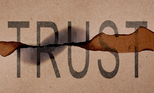 Pieces of paper with word Trust and burnt edges. Betrayal