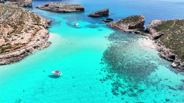 Blue Lagoon Bejn il Kmiemen Comino Għajnsielem Malta between Comino and Cominotto Kemmunett with shallow limestone seabed reef patches and leisure boats anchored in mediterranean waters aerial shot