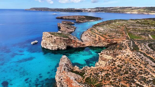 Comino Kemmuna Għajnsielem Gozo and Comino District Malta with stratified globigerina limestone cliffs and Blue Lagoon channel between Comino and Cominotto with Gozo coastline background forward glide