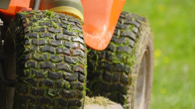 Ride-on Lawn Mower with Person Riding Wearing Outdoor Wellies as Vehicle Turns Past Camera on Sunny Spring Day. Perfect for gardening, landscaping, or satisfying nature visuals.4K.
