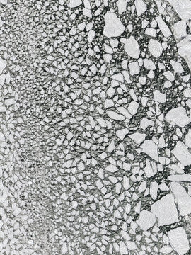 Aerial view of a vast, mesmerizing mosaic of fractured ice shards, stark white against the dark, frigid water, Hono, Vastra Gotaland County, Sweden.