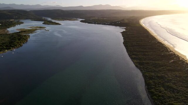 Aerial tilt-up over Keurbooms River lagoon and nature reserve at sunrise, Plett