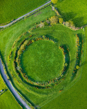 Aerial view of the ancient Iron Age hillfort of Castle Dore with circular earthwork ramparts and green fields Par, England, United Kingdom.