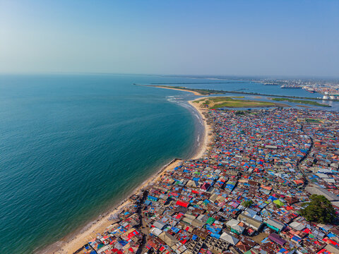 Aerial view of the vibrant juxtaposition of the dense urban sprawl meeting the serene coastline, a dance between human habitation and the vast Atlantic Ocean, Monrovia, Liberia.
