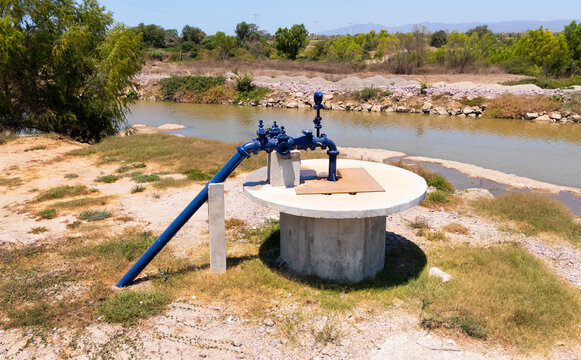 Aerial view of a striking blue water pump standing starkly against the parched earth and murky river, Puerto Vallarta, Jalisco, Mexico.