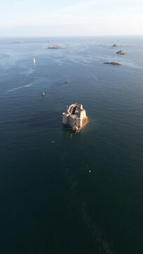 Aerial view of the formidable Chateau du Taureau standing defiant against the sea's embrace, a stone sentinel amidst the vast blue canvas, Plouezoc'h, Bretagne, France.