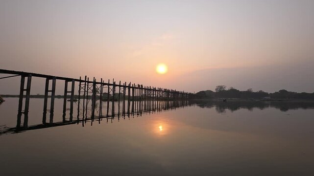 Silhouette and reflection on the water of U Bein Bridge at Sunset in Mandalay, Myanmar