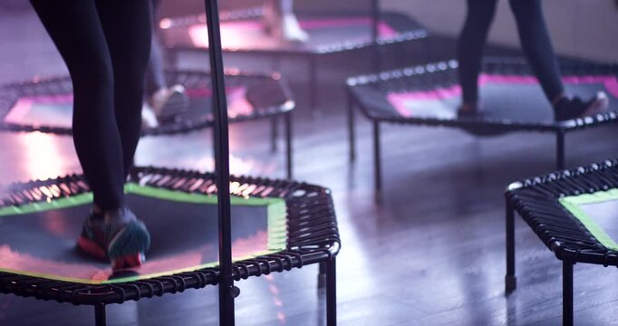 Group of people jumping on small trampolines during fitness class in brightly lit studio