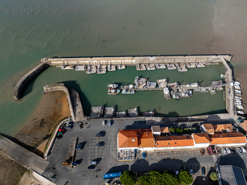 Aerial view of a harbor filled with boats, contrasting the deep blue water with the light tan of the surrounding land, Port Ostreicole de Bourcefranc-le-Chapus, Bourcefranc-le-Chapus, France.