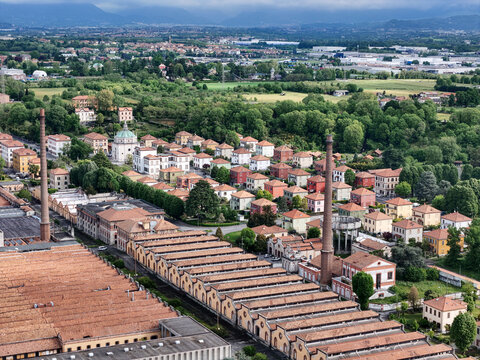Aerial view of the Industrial Village of Crespi d'Adda with historic factory buildings, tall brick chimneys, and residential houses in Capriate San Gervasio, Lombardia, Italy.