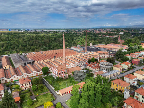 Aerial view of the Industrial Village of Crespi d'Adda featuring historic factory buildings with red-tiled roofs and tall brick chimneys in Capriate San Gervasio, Lombardia, Italy.