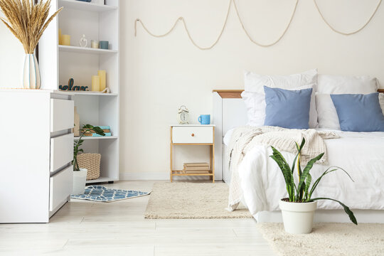 Interior of light bedroom with table, shelf unit and commode