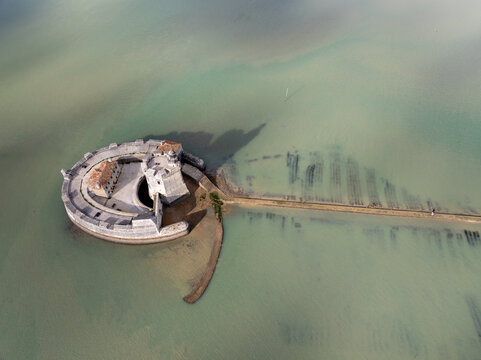Aerial view of a circular fortress with stone walls and a central tower, connected to the shore by a narrow strip of land, Bourcefranc-le-Chapus, France.