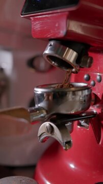 Coffee beans being ground into a portafilter on an espresso machine. Coffee preparation in a cafe