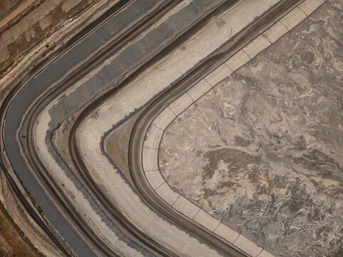 Aerial view of vast, curving industrial basins with dark, still water contrasting against dry, textured earth, Tucson, Arizona, United States.