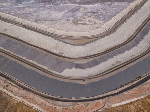 Aerial view of the vast, terraced basin with its stark, curving layers of grey and beige leading to a pale, dry expanse, Tucson, Arizona, United States.