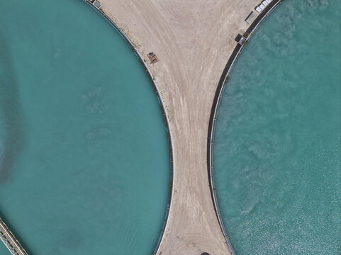Aerial view of brilliant turquoise waters sharply divided by a curving beige landmass, a vivid contrast of color and texture, Tucson, Arizona, United States.