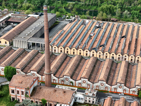 Aerial view of the Industrial Village of Crespi d'Adda with its iconic tall brick chimney and historic sawtooth factory roofs in Capriate San Gervasio, Lombardia, Italy.