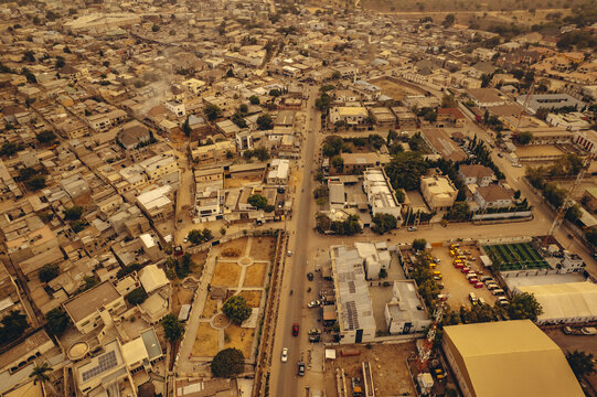 Aerial view of the sprawling urban landscape of Tarauni, where dusty orange rooftops meet green trees and busy roads, Tarauni, Kano, Nigeria.