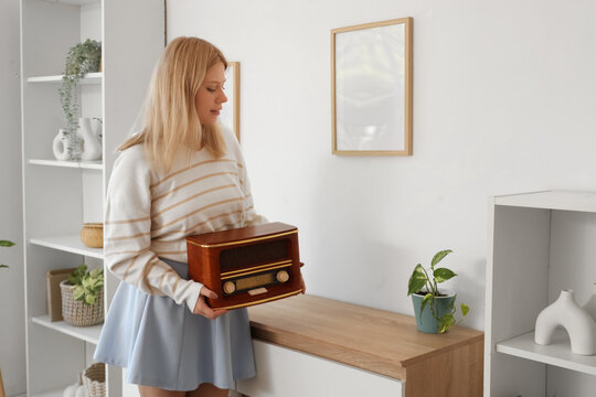 Female interior designer putting retro radio receiver on commode in living room