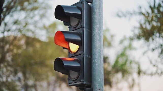 Traffic light changing from green to red, signaling stop in urban environment with soft background, 4K
