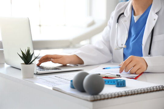 Female doctor working with laptop at desk in office, closeup