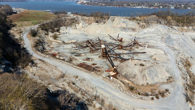 Aerial view of a quarry, with rusted machinery amidst pale stone and winding paths, leading to the distant water, Tomkins Cove, New York, United States.