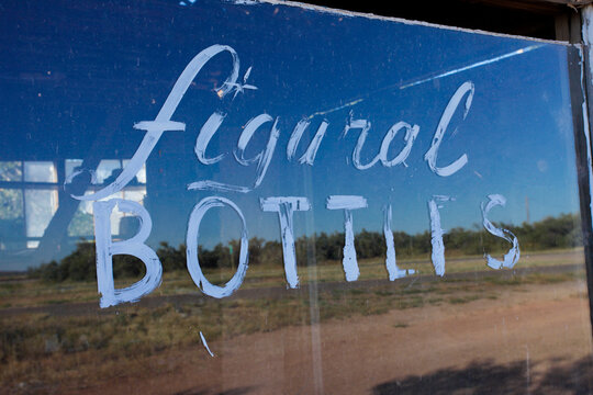 Hand-painted &ldquo;Figural Bottles&rdquo; window sign on old abandoned building