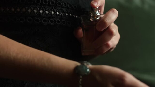 Woman spraying perfume on her hand. Close up female hands with perfume bottle.