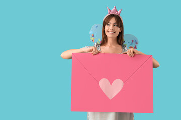Naklejka premium Young woman in fairy costume with big paper envelope on blue background
