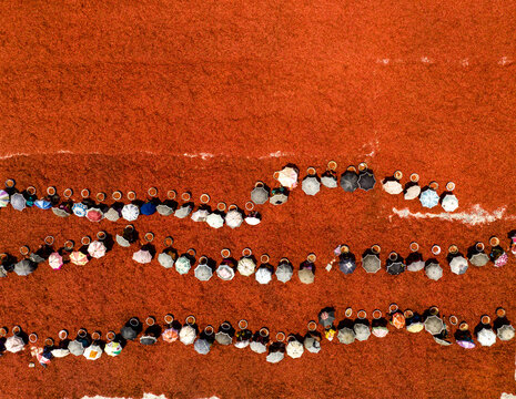 Aerial view of a vibrant tapestry of individuals gathered in solemn unity on an earthy red expanse, Sariakandi, Rajshahi Division, Bangladesh.