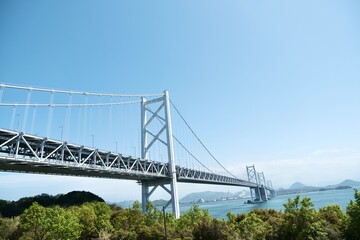 Fototapeta premium Large Suspension Bridge Over Blue Sea Under Clear Sky