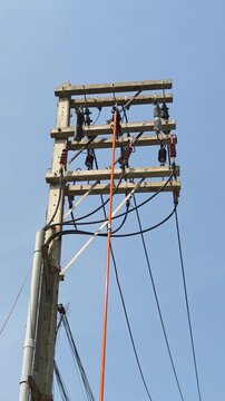 Utility lineman using hot stick to open drop out fuse on distribution power pole.